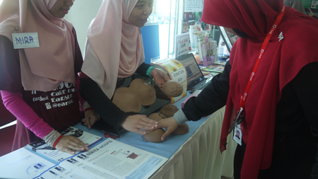 Sukarelawan CaRE sedang mengajar pengunjung tentang cara-cara pemeriksaan sendiri payudara di booth pameran